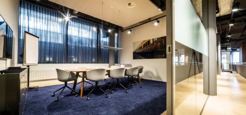 Professional office space rental at Kennemerplein 6-14, with a well-lit conference room featuring modern furniture and large windows in Haarlem Centraal Station area.