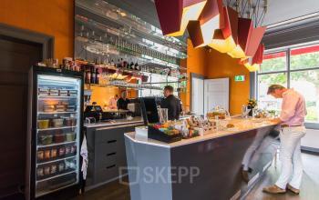 Sleek office space rental at Nieuwe Gracht 3, Haarlem Centrum, featuring a modern pantry with people actively engaged in business conversations.