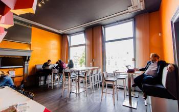Modern office space rental at Nieuwe Gracht 3, Haarlem Centrum, with vibrant, colorful decor and windows offering ample natural light, while professionals engage in business activities.