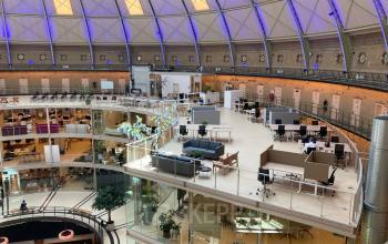Bright, open office space rental at Koepelplein 1E, Haarlem Centrum, featuring modern workstations and elegant meeting areas under a striking domed roof.