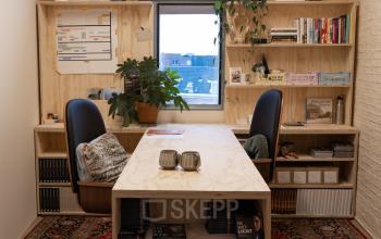 Charming office space rental at Koepelplein 1E in Haarlem Centrum, featuring a cozy workspace with wooden shelves, two modern chairs, and a vibrant red carpet.