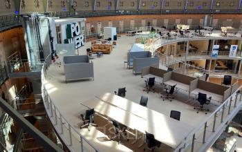 Spacious, modern office space rental inside Koepelplein 1E, featuring multiple workstations, comfortable seating areas, and a unique architectural design with a high ceiling.