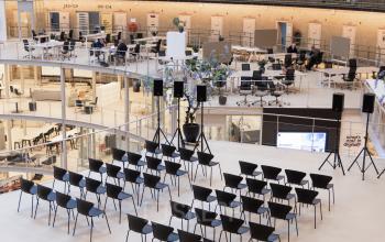 Spacious and modern office interior at Koepelplein 1E, Haarlem Centrum, featuring rows of chairs set up for a presentation, surrounded by workspaces. Ideal for office space rental with versatile uses.