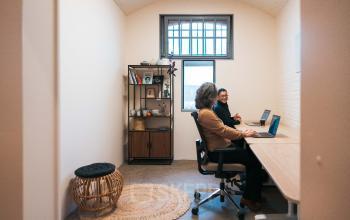 Two professionals working at desks in a cozy office space at Koepelplein 1E, Haarlem Centrum. Featuring natural light and modern furnishings, this office space rental offers a productive work environment.
