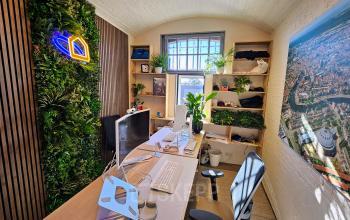 Bright, modern office with greenery on the walls, a large city map artwork, and two computer workstations at Koepelplein 1E, Haarlem. Ideal office space rental for creative professionals.