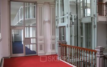 Interior view of office space at Wilhelminastraat 43A, Haarlem Centrum, Haarlem, featuring a modern glass elevator and carpeted floors.