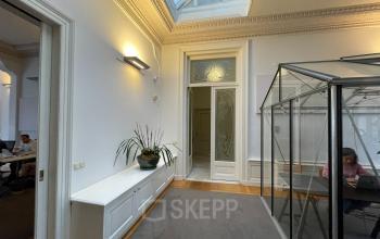 Interior space at Nieuwe Gracht 74-76 in Haarlem Centrum, featuring a glass office pod and a plant on a white cabinet, suitable for office space rental.