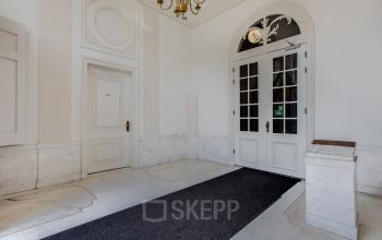 Entrance area of Nieuwe Gracht 74-76 office in Haarlem Centrum with high ceilings, chandelier, and marble flooring, ideal for office space rental.