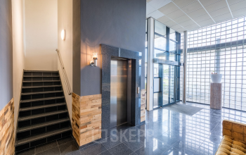Modern interior of an office building at Mollerusweg 84, Haarlem Waarderpolder, with staircase, elevator, and ample natural light, suitable for office space rental.