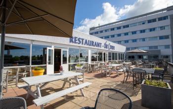 Outdoor patio area at Mollerusweg 84 in Haarlem Waarderpolder, with tables and chairs under umbrellas near an office building and a restaurant.