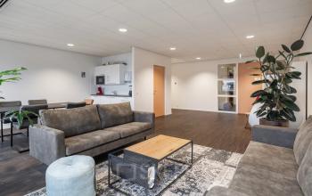 Furnished office lounge at Mollerusweg 84, Haarlem Waarderpolder, featuring a seating area with sofas and a small kitchen, ideal for rent office space.