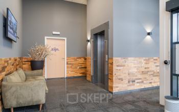 Well-lit entrance area with wood paneling and a couch at Mollerusweg 84, Haarlem Waarderpolder, perfect for those seeking office space rental.