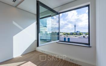 Bright office space for rent at Mollerusweg 84 in Haarlem Waarderpolder, featuring large windows with a view, carpeted floor, and ample natural light.