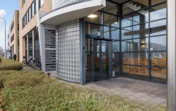 Exterior view of the office building at Mollerusweg 84, Haarlem Waarderpolder, showcasing glass entrance doors and a directory sign, ideal for those seeking office space rental.