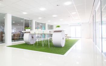 Modern, bright communal workspace with high tables and stools, featuring glass walls and green decor located at A. Hofmanweg 5A, Haarlem Waarderpolder.