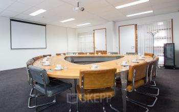 Conference room at A. Hofmanweg 5A, Haarlem Waarderpolder, Haarlem, featuring a large U-shaped table with chairs, a projector, and a screen for office space rental.