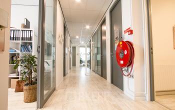 Bright hallway in Haarlem Waarderpolder's office to rent, featuring glass doors and a wooden floor.