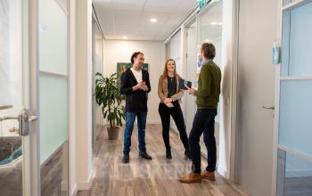 Three people engaged in a discussion in a modern office hallway at Waarderweg 19, highlighting the collaborative environment of this office space rental in Haarlem Waarderpolder.
