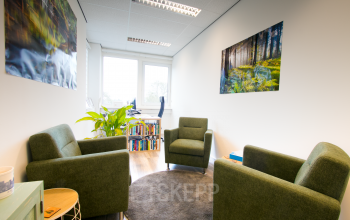 Cozy office space at Waarderweg 19, Haarlem Waarderpolder, featuring green armchairs, nature-themed artwork, and a small bookcase. Ideal for rent office space needs.
