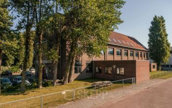 Exterior view of office building at Hendrik Figeeweg 1E, Haarlem Waarderpolder, highlighting the brick facade and surrounding green trees.