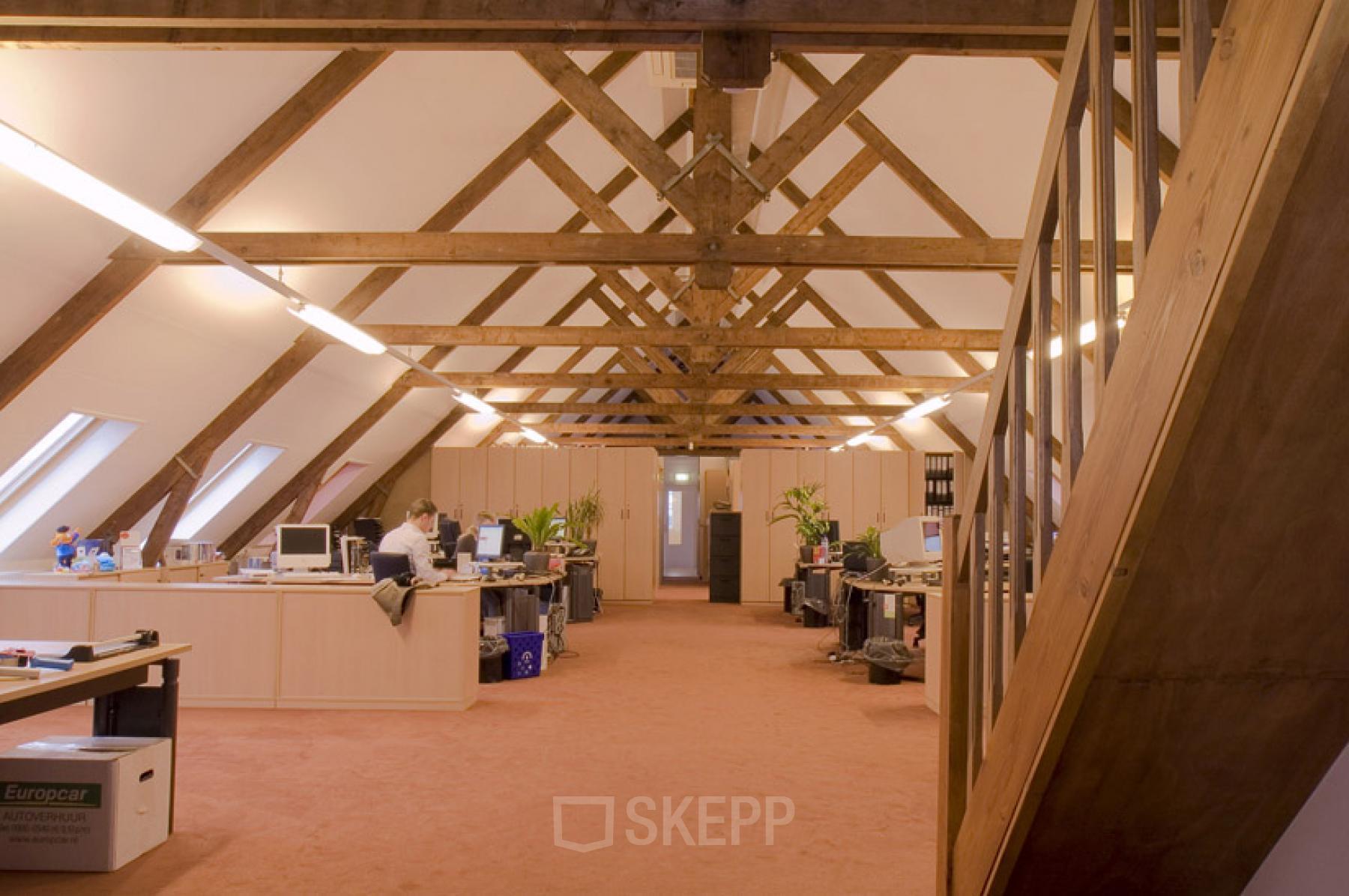 Spacious attic workspace with exposed wooden beams, furnished with desks and computers at Hendrik Figeeweg 1E, Haarlem Waarderpolder, Haarlem available for office space rental.