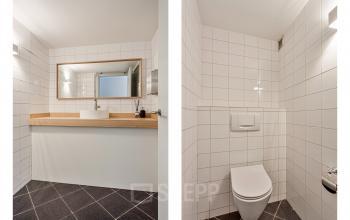 Modern restroom at Dreef 34 in Haarlem Zuid. Features sleek white tiles and wooden counter, suitable for businesses seeking office space rental.