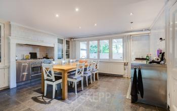 Spacious pantry area in the office at Dreef 36, Haarlem Zuid, Haarlem, featuring a long wooden table, white chairs, modern kitchen appliances, and large windows allowing natural light.