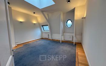 Spacious empty office space with blue carpet, white walls, ceiling lights, and large windows located at Dreef 36, Haarlem Zuid.