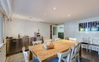Spacious pantry in the office to rent at Dreef 36, Haarlem Zuid, Haarlem, featuring a large wooden table, white chairs, and a kitchen area with cabinets and appliances.
