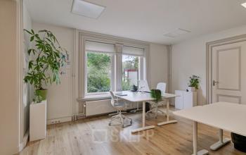 Bright office space with large windows, wooden flooring, white desks, and green plants for rental located at Florapark 7, Haarlem Zuid, Haarlem.