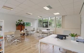 Well-lit office space at Florapark 7, Haarlem Zuid, featuring modern furnishings, white desks, ergonomic chairs, and large windows with garden views.