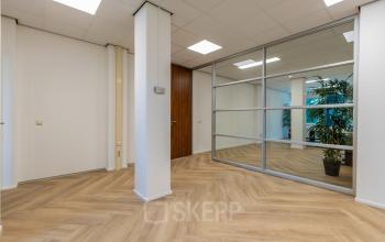 Interior view of office space at Fonteinlaan 5, Haarlem Zuid, Haarlem, featuring a modern design with wooden flooring, glass partition walls, and a potted plant.