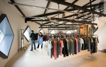 Modern office space rental at Suikersilo Oost-West 1-41, Halfweg, showcasing a professional clothing showroom interior with businesspeople examining merchandise.