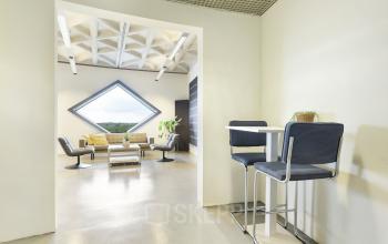 Contemporary office space rental at Suikersilo Oost-West in Halfweg, featuring stylish seating and a unique diamond-shaped window.