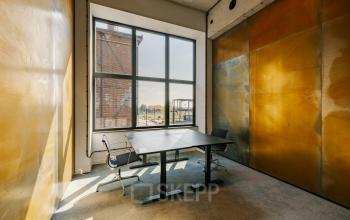 Bright office space at Haarlemmerstraatweg 13, Halfweg, featuring a large window with natural light pouring in, glass partition walls, and modern office chairs. Ideal office to rent for professionals seeking a vibrant workspace.