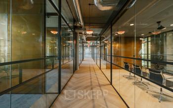 Modern office hallway at Haarlemmerstraatweg 13, Halfweg with glass-walled conference rooms and sleek wooden flooring, ideal for office space rental.