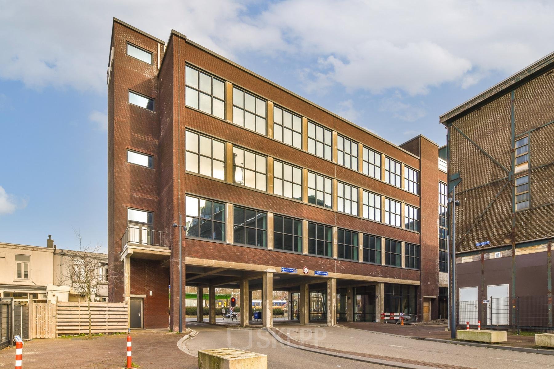 Exterior view of an office building at Haarlemmerstraatweg 13 in Halfweg, perfect for office space rental, featuring large windows and modern brick design.