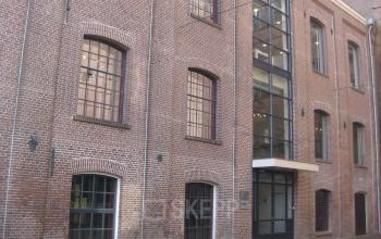 Exterior view of the brick office building located at Haarlemmerstraatweg 11, Halfweg. Large windows and a glass entrance highlight the facade, an attractive setting for office space rental.