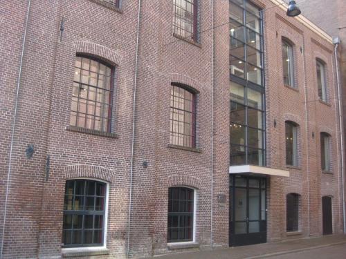 Exterior view of the brick office building located at Haarlemmerstraatweg 11, Halfweg. Large windows and a glass entrance highlight the facade, an attractive setting for office space rental.