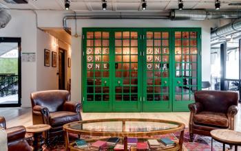 Interior view of the office space for rent at Rödingsmarkt 9 in Hamburg Old Town, featuring eclectic seating and a meeting area with green framed glass doors.