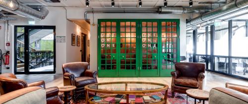 Interior view of the office space for rent at Rödingsmarkt 9 in Hamburg Old Town, featuring eclectic seating and a meeting area with green framed glass doors.
