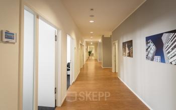 Bright hallway at Raboisen 38, Hamburg Old Town, ideal for office space rental. The corridor leads to various rooms, featuring artwork on the walls.
