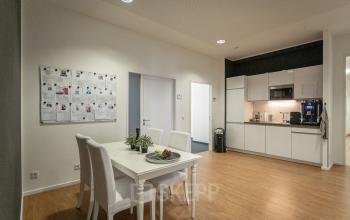 Interior view of a furnished office space at Raboisen 38, Hamburg Old Town, featuring a dining area and kitchenette, available for office space rental.