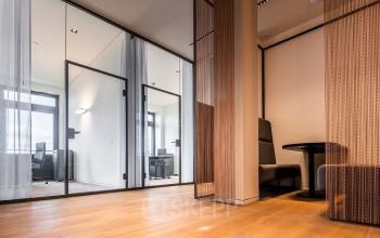 Moderner Büroraum zur Miete in Ballindamm 27, Hamburg Altstadt, mit hellem Holzboden, Glastrennwänden und stilvollen Möbeln für produktives Arbeiten.