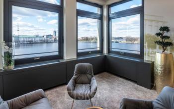 Helles Büro am Ballindamm 27 in Hamburg Altstadt mit großen Fenstern und Seeblick, ideal zur Büroraum mieten. Gemütliche Sitzmöbel und moderne Einrichtung schaffen eine angenehme Arbeitsatmosphäre.