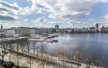 Blick auf den Ballindamm 27 in Hamburg Altstadt mit Wasser und städtischen Gebäuden im Hintergrund.