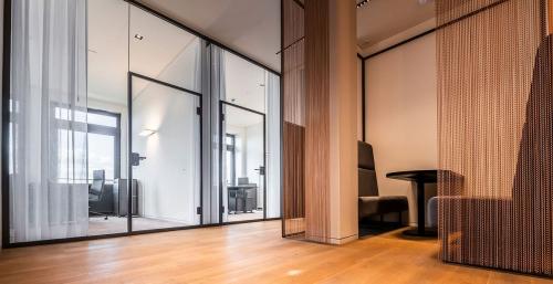 Modern office space in Hamburg Old Town with glass partitions, wooden flooring, and sleek furnishings, ideal for those seeking office space rental. Bright, clean, and professional environment.