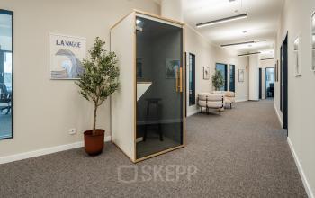 Modern hallway in an office building at Überseeallee 1, Hamburg Hafencity, featuring stylish decor and private phone booth. Ideal for office space rental.