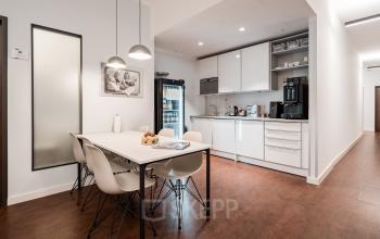 Modern office pantry in Überseeallee 1, Hamburg Hafencity featuring sleek white cabinets, a coffee machine, and a dining table with chairs, perfect for informal meetings or work breaks. Ideal office space rental.