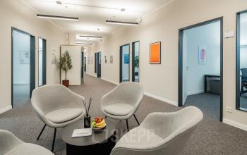 A modern office interior at Überseeallee 1, Hamburg Hafencity, featuring furnished workspaces with comfortable seating and decorative plants, ideal for office space rental.
